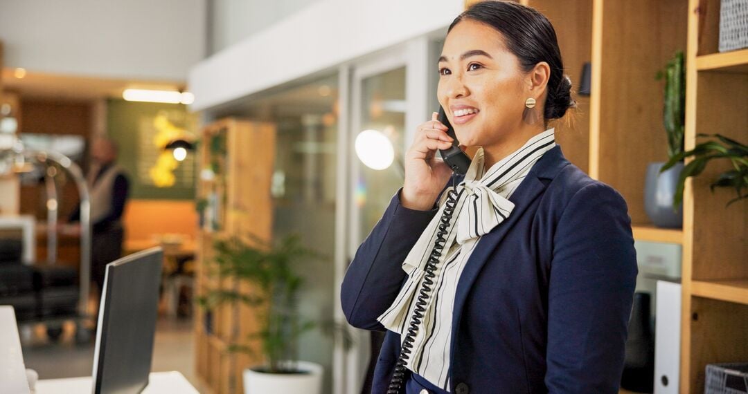 Web_Desktop-Woman, phone call and happy at hotel, concierge and talk with client for booking information. Person, help desk and receptionist with tel